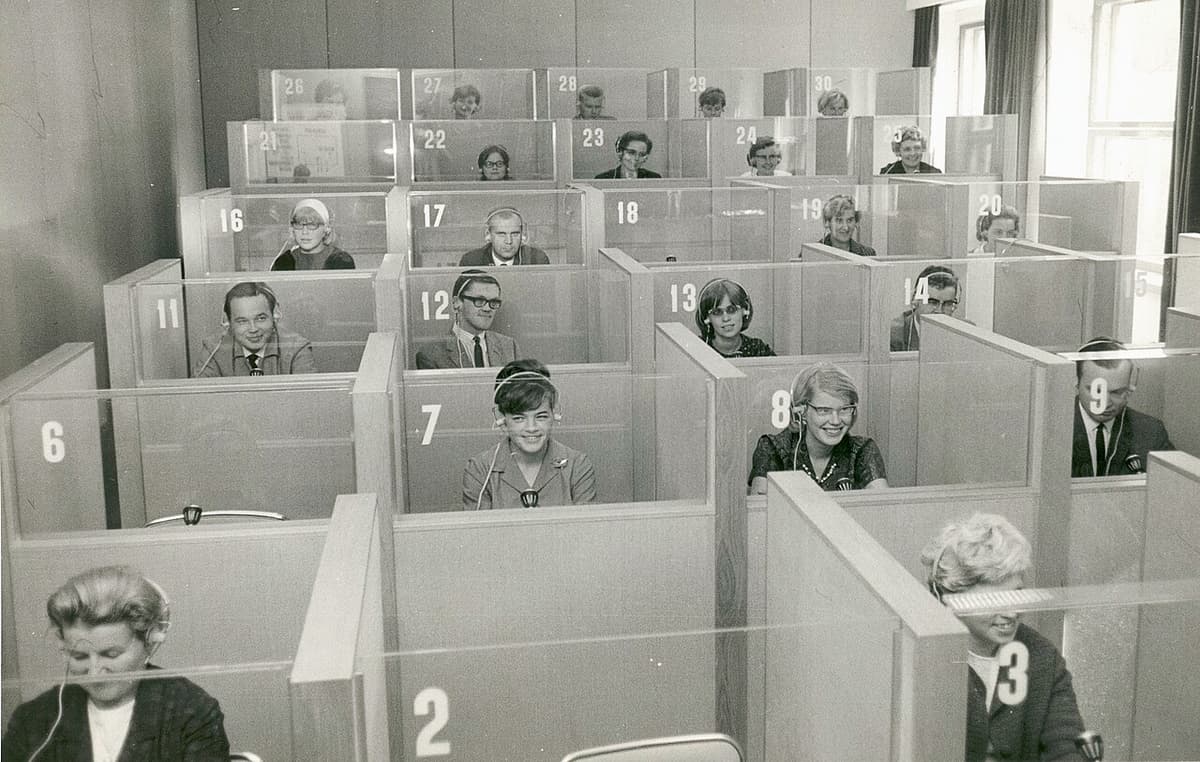 Students with headsets in a 1960s language laboratory, the kind of listening booth where early shadowing language learning research took shape